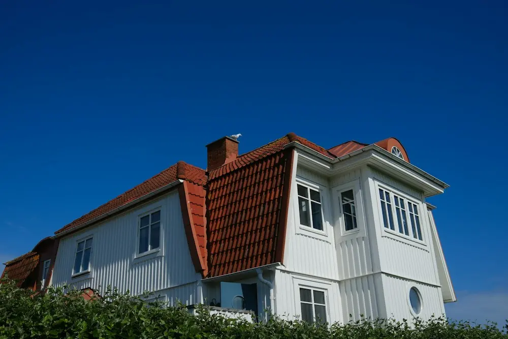 Balta māja ar sarkanu dakstiņu jumtu
